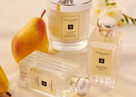 English Pear and Freesia colognes en kaars op een tafel met een peer